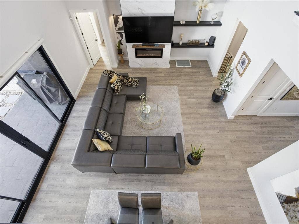 Second floor view of living room with light wood-style floors and a glass covered fireplace