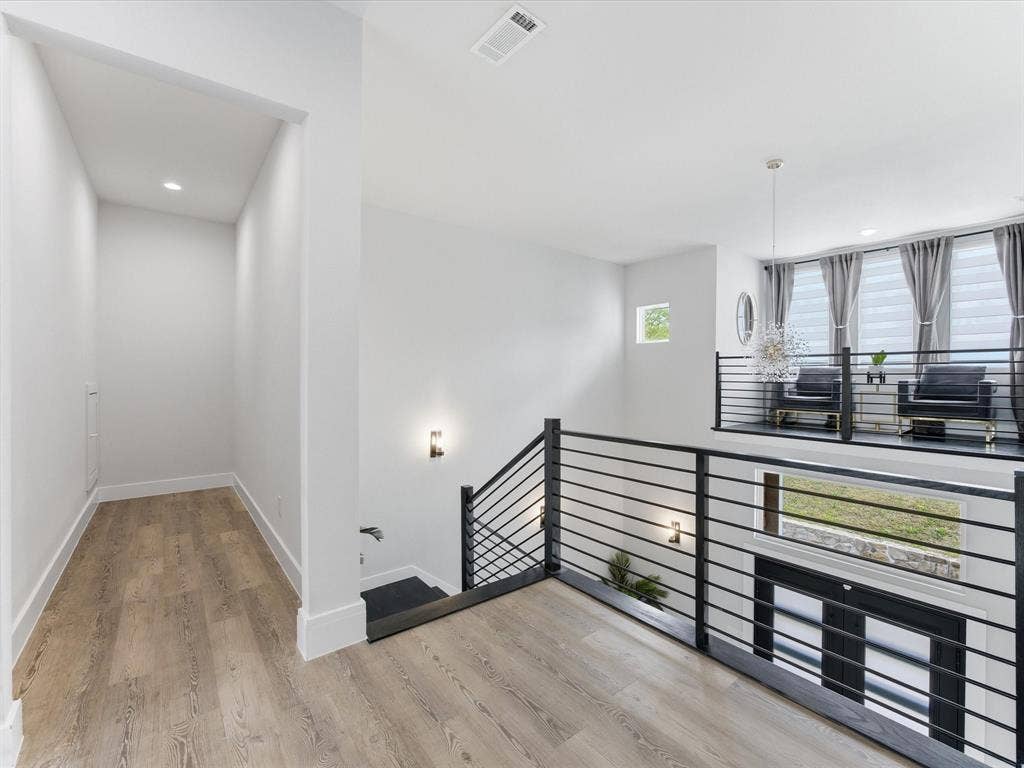 Stairway featuring wood finished floors and suspended lighting