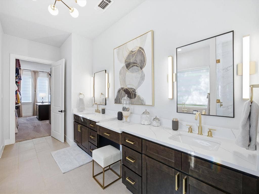 Bathroom featuring double vanity, plenty of natural light, hanging lights, and a marble finish shower