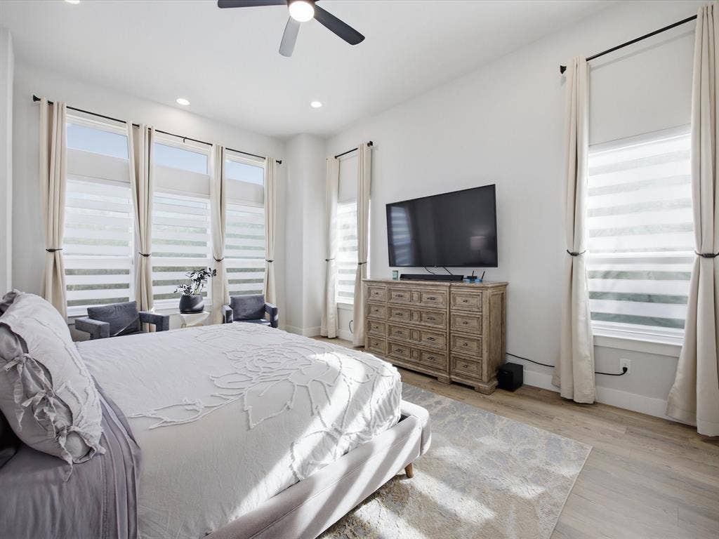 Bedroom featuring multiple windows, ceiling fan, light wood-style flooring, and recessed lighting