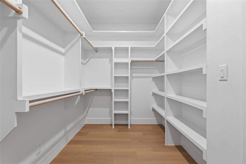 3424 Navaro Street, Dallas, TX 75212 Walk-in closet featuring built-in white shelving, multiple hanging rods, and wood-finish flooring