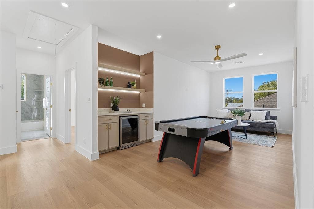 3424 Navaro Street, Dallas, TX 75212 Light wood-finish flooring throughout, integrated wet bar with built-in beverage refrigerator, two large windows, recessed lighting, and a ceiling fan
