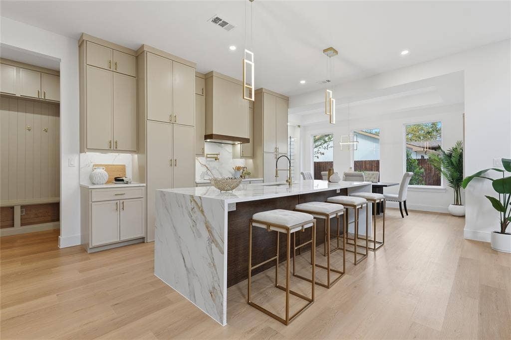 3424 Navaro Street, Dallas, TX 75212 Expansive kitchen island with a waterfall countertop, light-toned cabinetry, wood-finish flooring, and contemporary pendant lighting