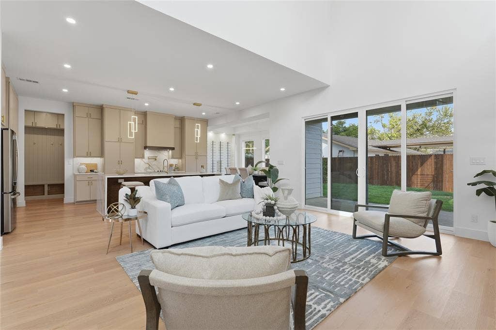 3424 Navaro Street, Dallas, TX 75212 Vaulted ceiling with recessed lighting, light wood-finish flooring, full wall of sliding glass doors, white shaker cabinetry with gold hardware, and stainless steel appliances