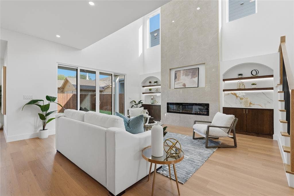 3424 Navaro Street, Dallas, TX 75212 Vaulted ceilings, wood-finish flooring, full-height fireplace, built-in shelving with integrated lighting, and a sliding glass door