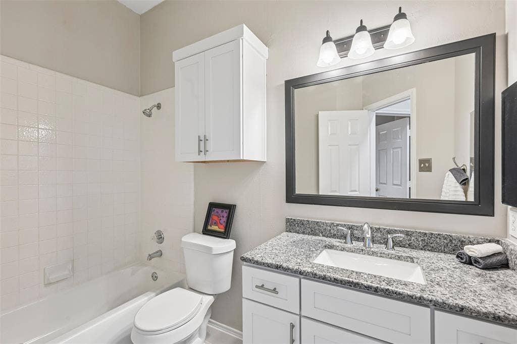White vanity with granite countertop, undermount sink, and polished chrome faucet