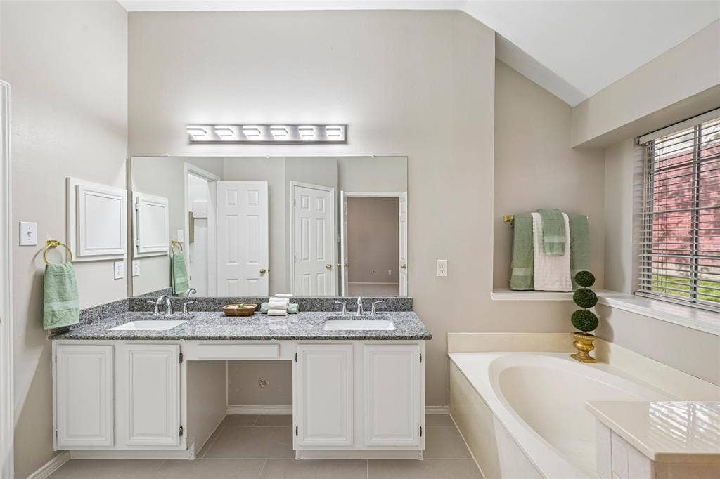 Dual vanity with undermount sinks, granite-style countertop, and white cabinetry