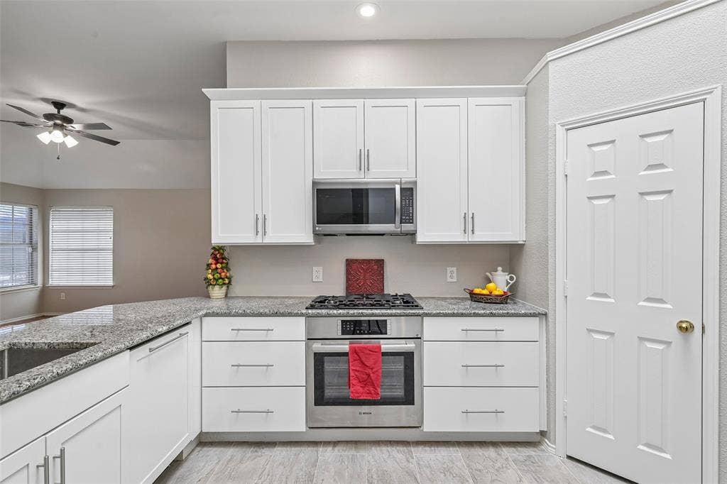 White shaker cabinetry, stainless steel appliances, built-in microwave, gas cooktop, and wood-finish flooring