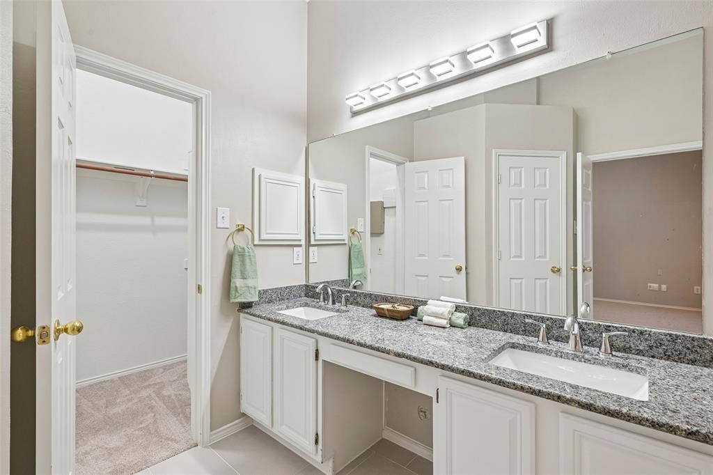Double vanity with undermount sinks, speckled countertop, and wall-mounted light fixture