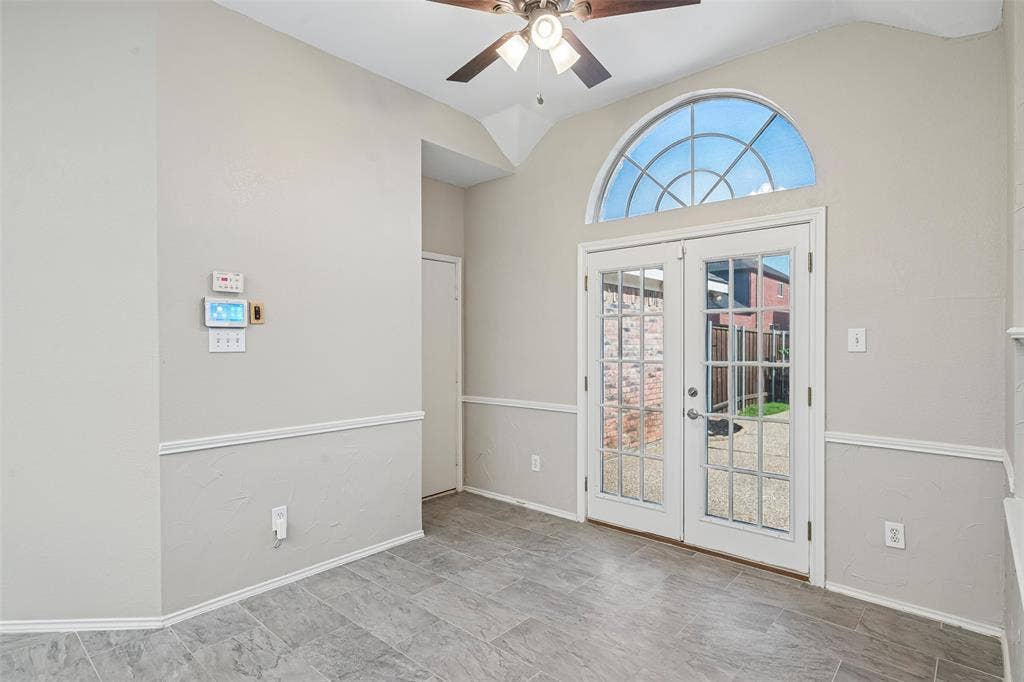Vaulted ceiling, ceiling fan, French doors with full lites, arched transom window, and tile flooring