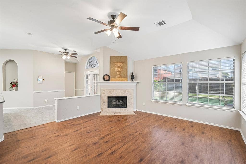 Vaulted ceilings, wood-finish flooring, and a fireplace with a stone surround