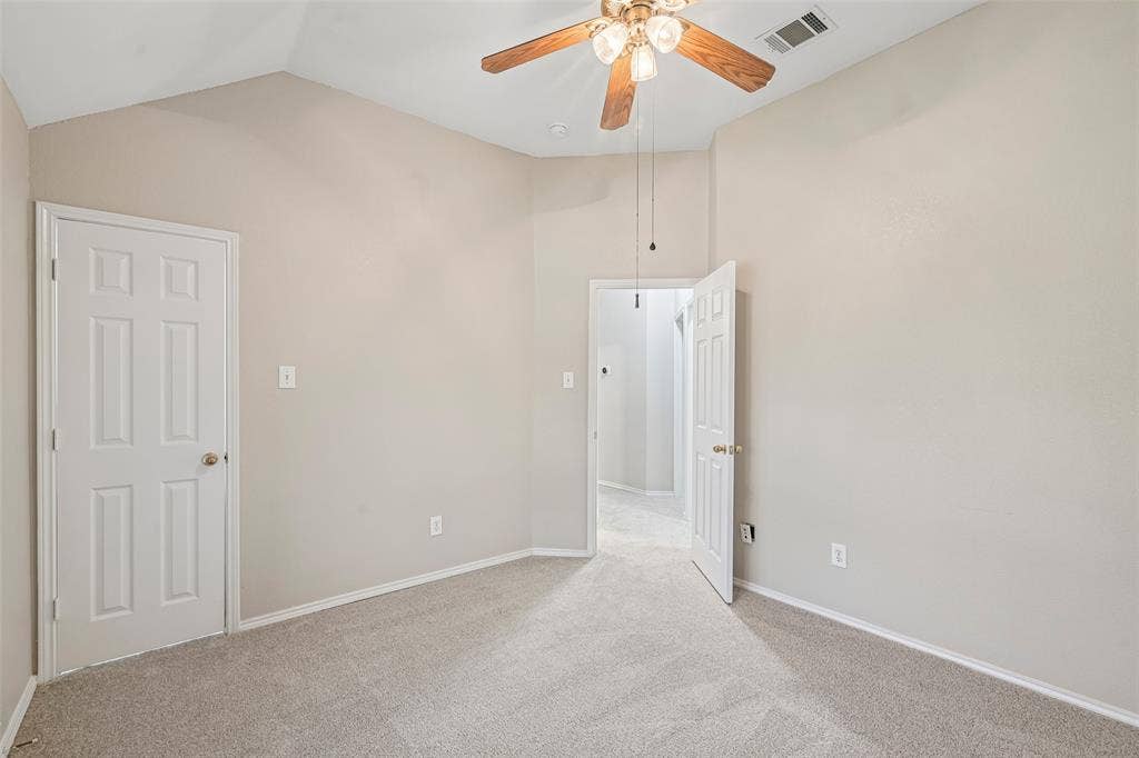 Vaulted ceiling with a ceiling fan, light-colored carpeting, white baseboards, and paneled doors