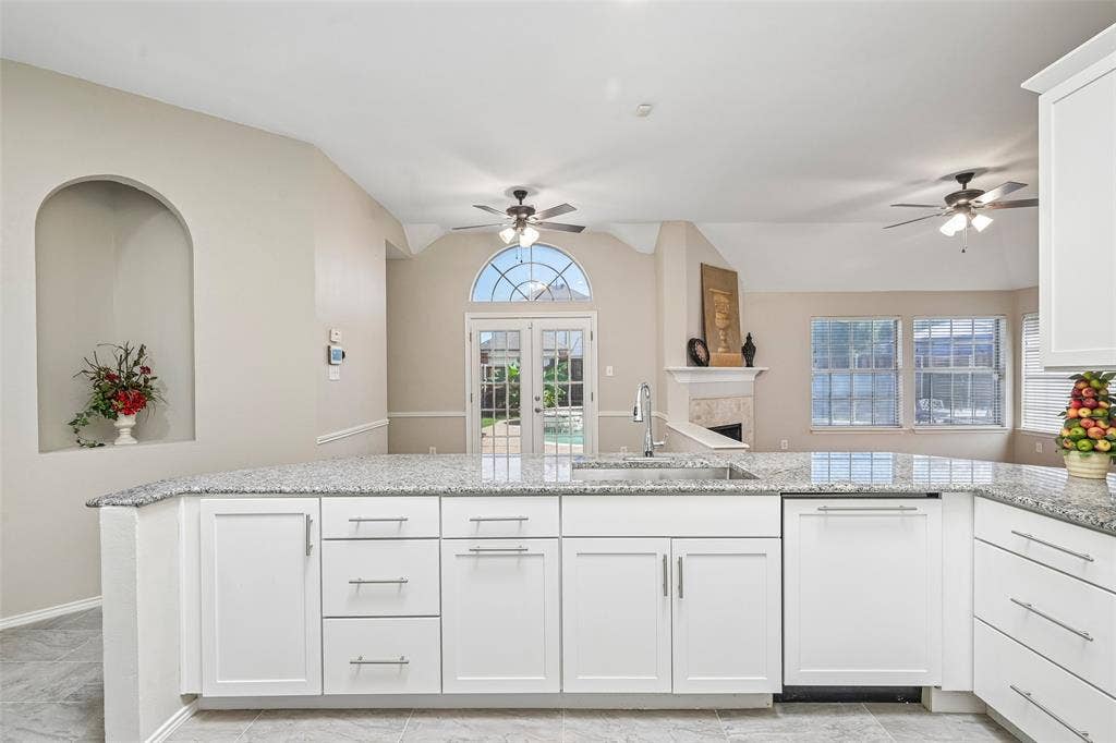 Kitchen island with a stainless steel sink, chrome faucet, and white shaker-style cabinetry
