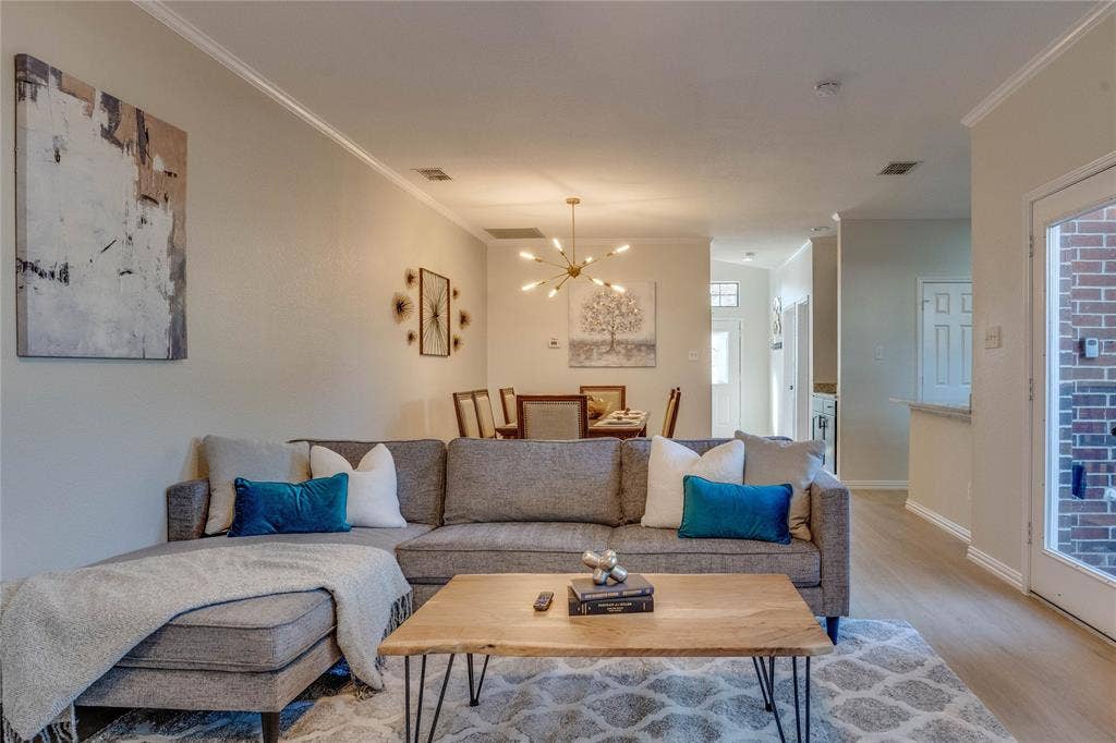6003 Lloyd Court, Dallas, TX 75252 Open-concept living space with crown molding, wood-finish flooring, and a modern chandelier