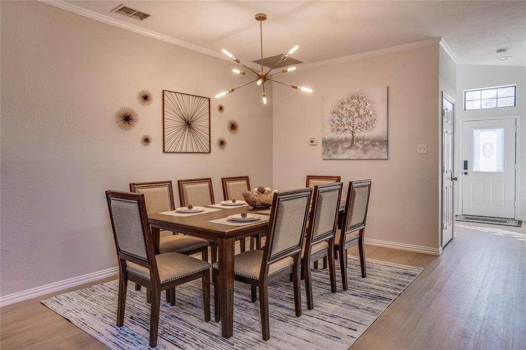 6003 Lloyd Court, Dallas, TX 75252 Dining area with a modern linear chandelier, crown molding, and wood-finish flooring