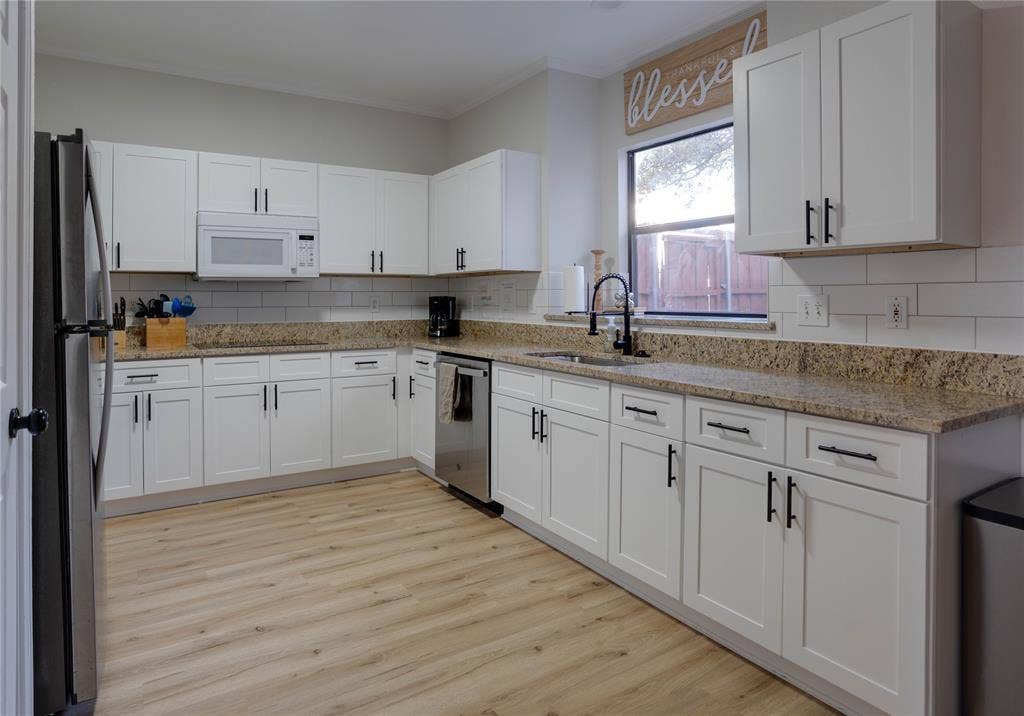 6003 Lloyd Court, Dallas, TX 75252 Kitchen featuring white cabinetry, light-toned wood-finish flooring, a stainless steel dishwasher, a black refrigerator, and a window above the sink
