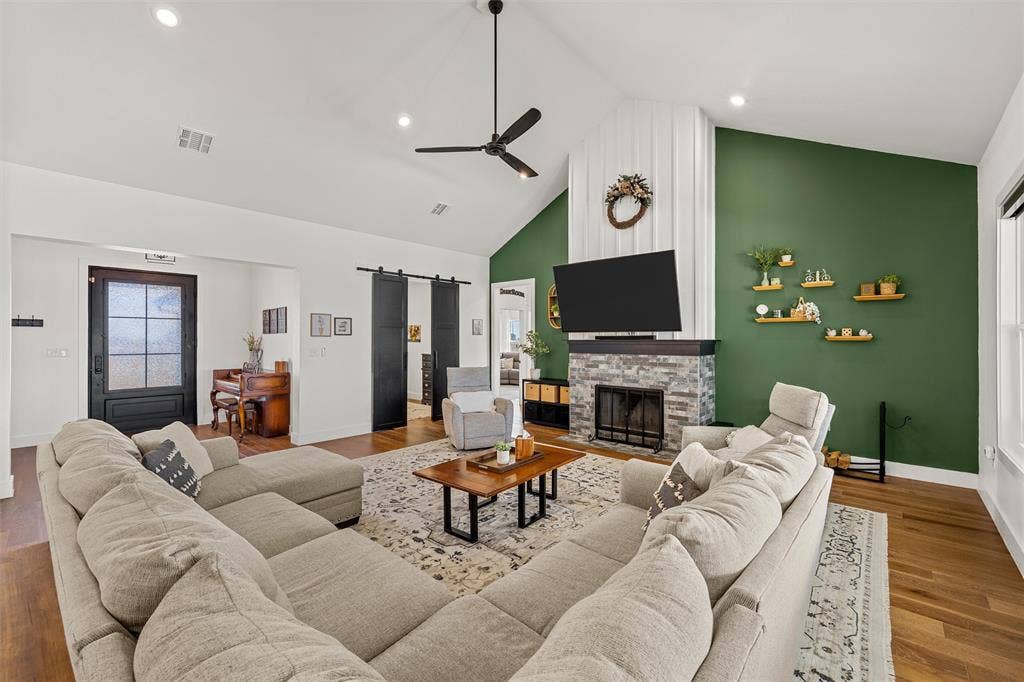 446 Wade Drive, Eddy, TX 76524 Vaulted ceilings with recessed lighting, wood-finish flooring, a stone-clad fireplace with a dark wood mantel, and built-in barn doors