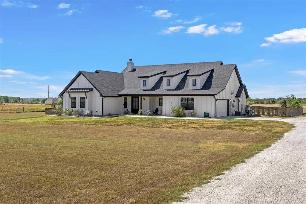 446 Wade Drive, Eddy, TX 76524 Modern farmhouse exterior with white board and batten siding, dark shingle roof, and multiple dormer windows