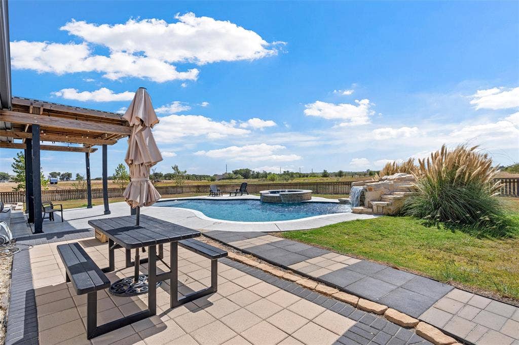446 Wade Drive, Eddy, TX 76524 Outdoor swimming pool with integrated spa, rock waterfall feature, paver patio, and an overhead pergola