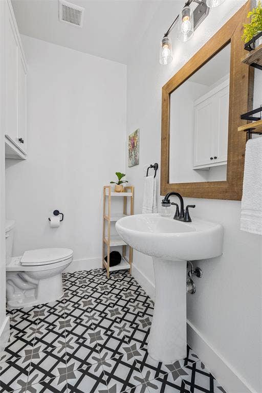 446 Wade Drive, Eddy, TX 76524 Pedestal sink with matte black faucet, patterned floor tiles, recessed wall cabinet, and a framed mirror (second on suite bathroom)