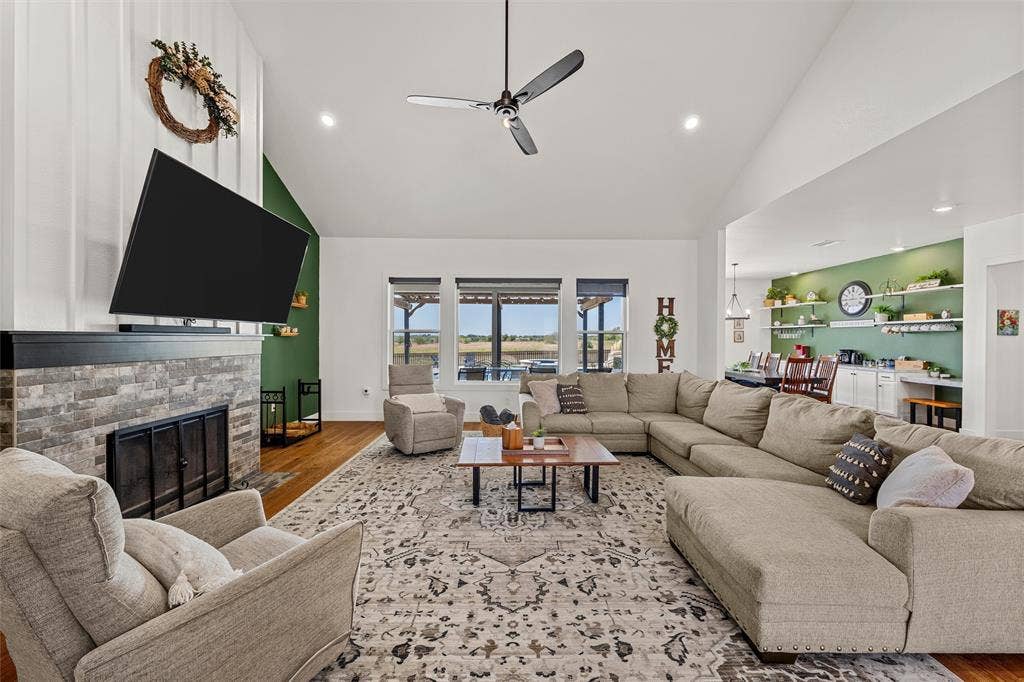 446 Wade Drive, Eddy, TX 76524 Vaulted ceiling with a ceiling fan, stone-clad fireplace with a dark mantel, wood-finish flooring, recessed lighting, and large windows