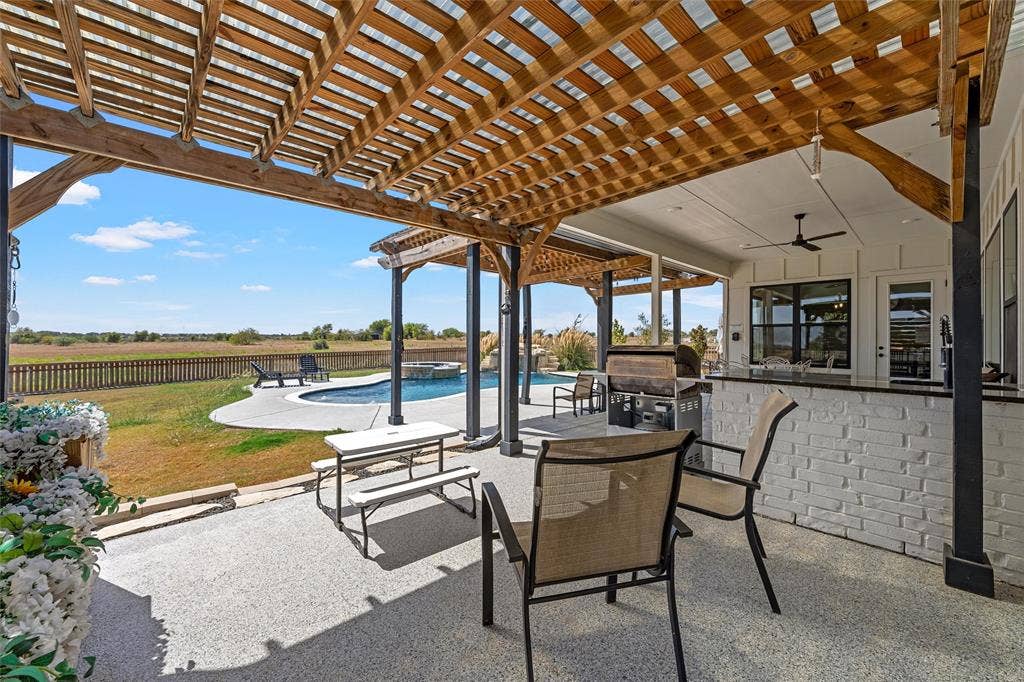 446 Wade Drive, Eddy, TX 76524 Expansive covered patio with a wood pergola, built-in outdoor kitchen with black countertops, and a swimming pool