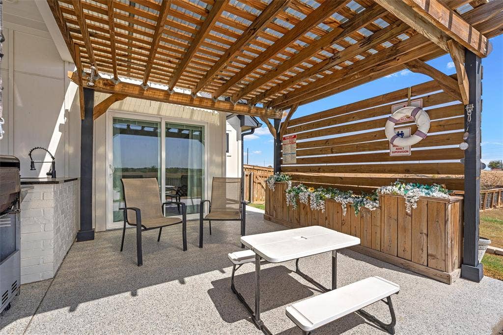 446 Wade Drive, Eddy, TX 76524 Covered patio featuring a wood pergola, built-in outdoor kitchen with a sink, white brick base, and sliding glass door access