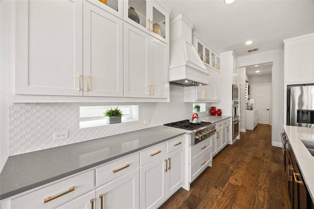 12512 Deer Trail, Frisco, TX 75035 White shaker cabinetry with gold-tone hardware, wood-finish flooring, built-in stainless steel oven, and a gas range