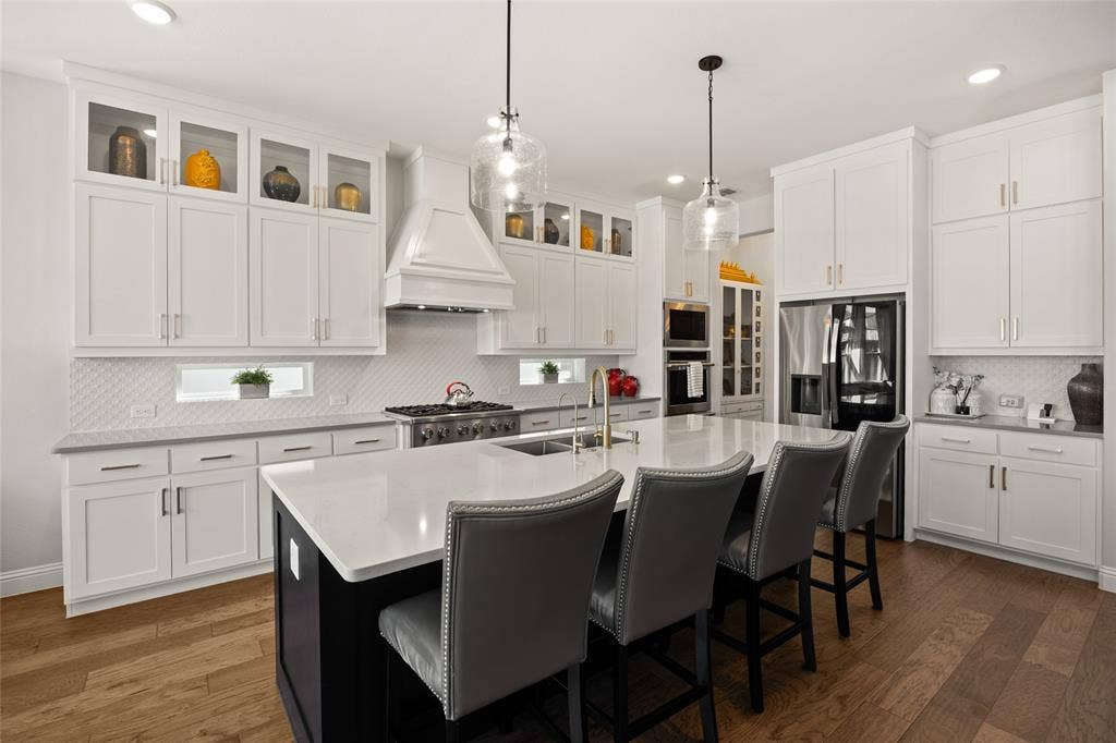 12512 Deer Trail, Frisco, TX 75035 Kitchen featuring white shaker cabinetry, an expansive center island with seating, a professional-grade range, a tile backsplash, and wood-finish flooring