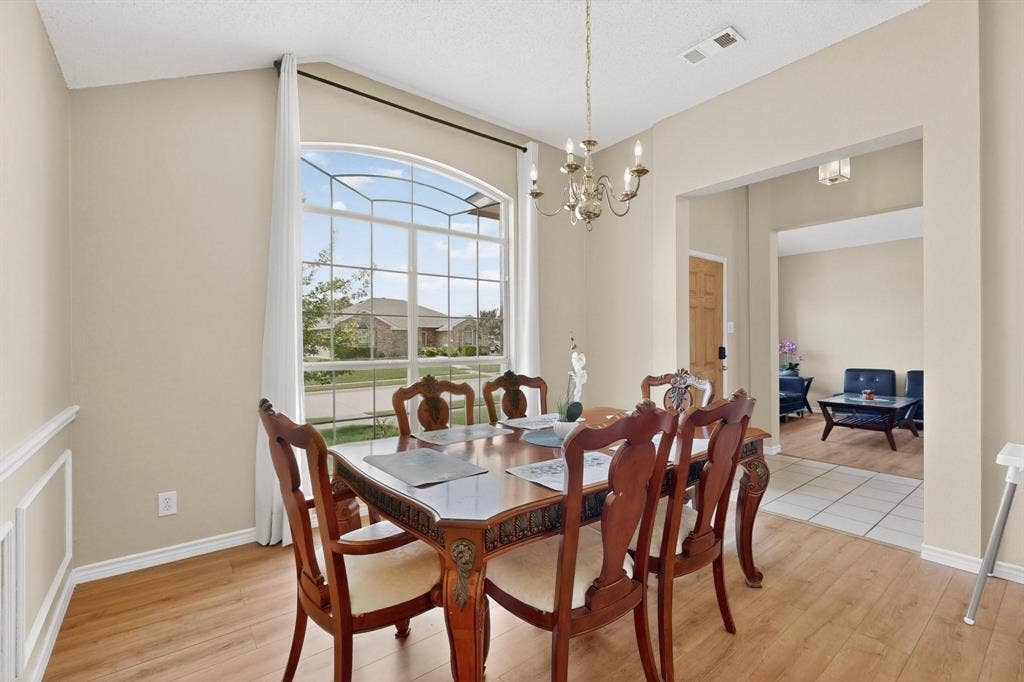 320 Elizabeth Trail, Murphy, TX 75094 Formal dining space featuring wood-finish flooring, an arched picture window, wainscoting, and a brass-tone chandelier
