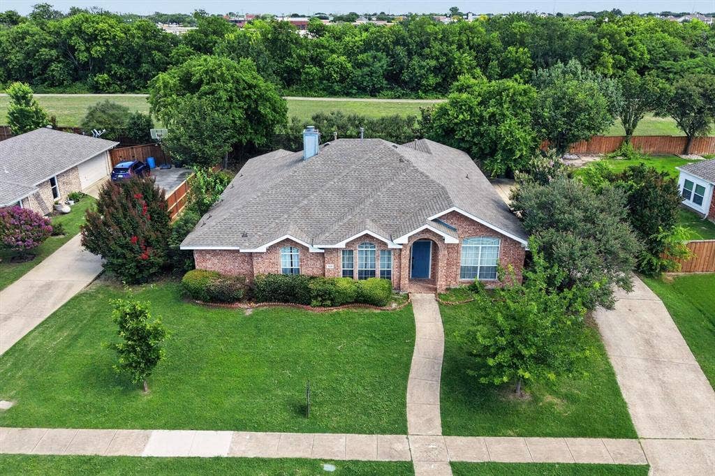 320 Elizabeth Trail, Murphy, TX 75094 Brick exterior with an arched entry, a concrete driveway, a concrete walkway, a shingled roof, and a mature tree