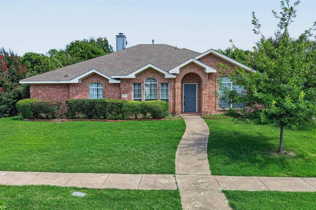 320 Elizabeth Trail, Murphy, TX 75094 Brick exterior with arched entry, complementing gray door, and established landscaping