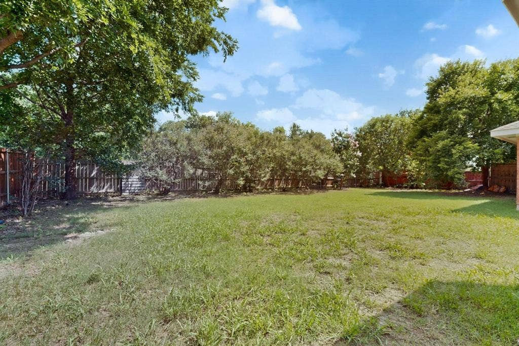 320 Elizabeth Trail, Murphy, TX 75094 Expansive grassy area with mature trees and a wood-panel fence