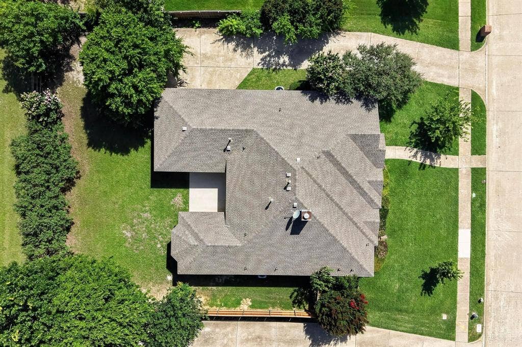 320 Elizabeth Trail, Murphy, TX 75094 Pitched shingle roof with multiple gables, surrounded by expansive green lawn, mature trees, and concrete walkways