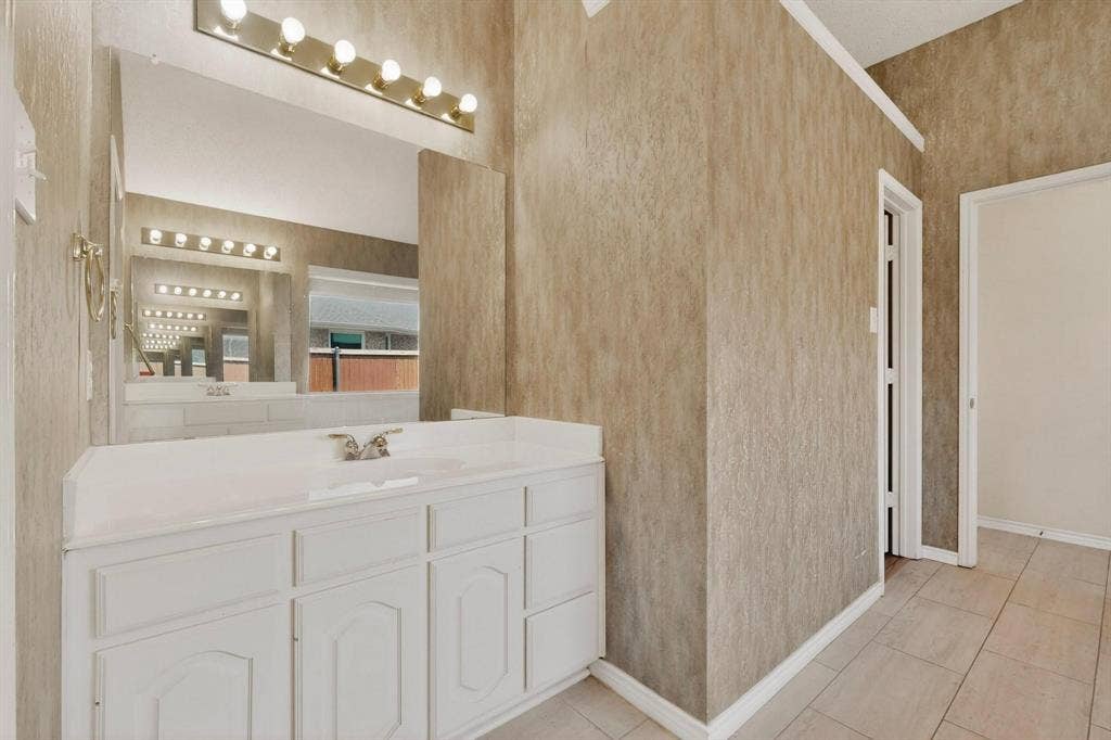320 Elizabeth Trail, Murphy, TX 75094 White vanity with paneled doors, integrated countertop sink, and a brass-finish faucet