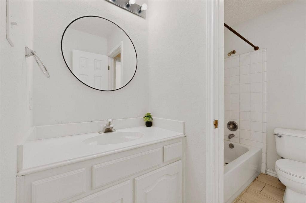 320 Elizabeth Trail, Murphy, TX 75094 White vanity with integrated sink, circular wall mirror, and overhead strip lighting