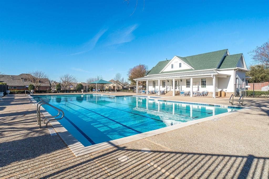 320 Elizabeth Trail, Murphy, TX 75094 Expansive outdoor swimming pool with lane lines, surrounding hardscaping, and a clubhouse with a covered porch