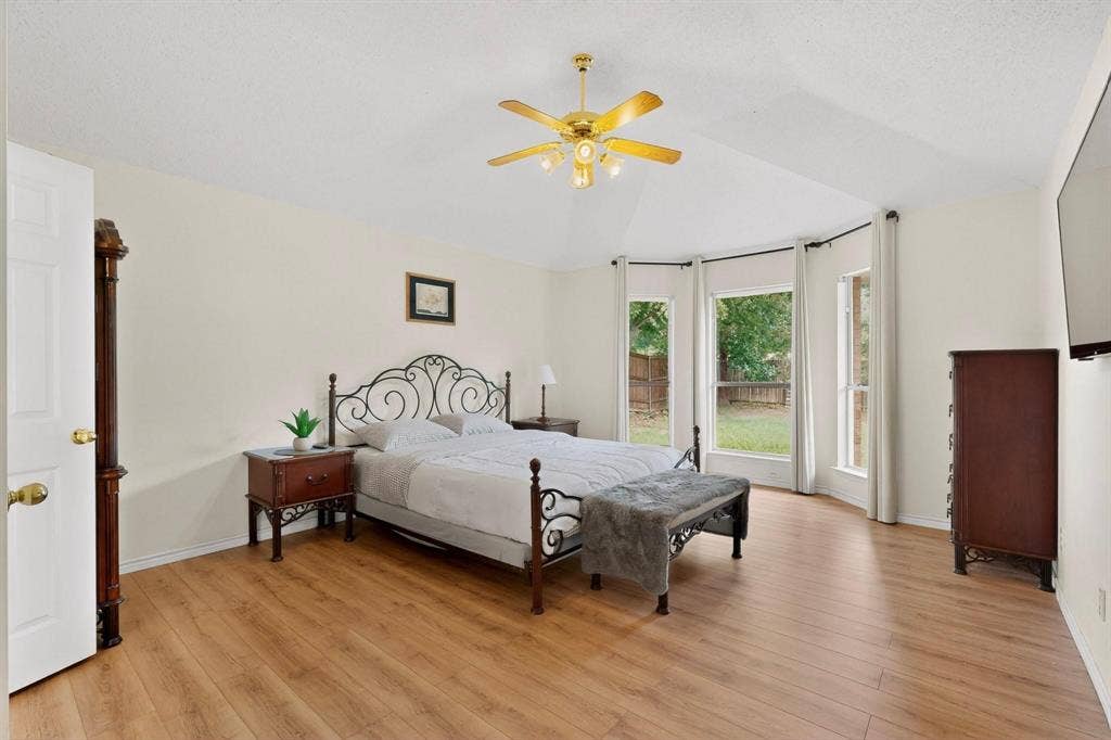 320 Elizabeth Trail, Murphy, TX 75094 Vaulted ceiling with a gold-tone ceiling fan, wood-finish flooring, and a bay window configuration