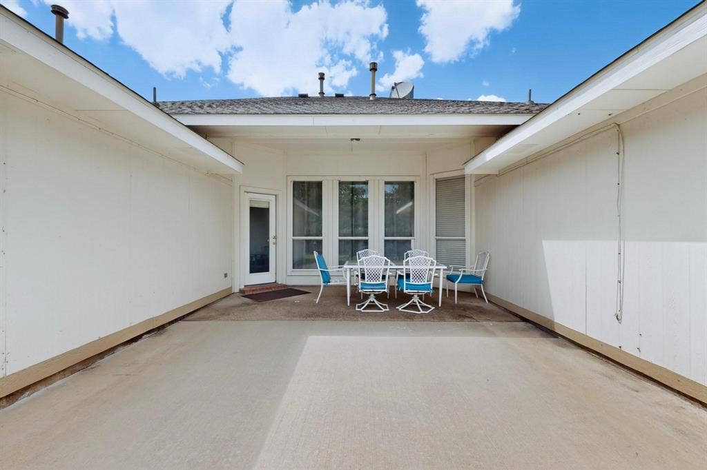 320 Elizabeth Trail, Murphy, TX 75094 Expansive concrete patio with an adjacent covered area, featuring a full-light exterior door and large windows
