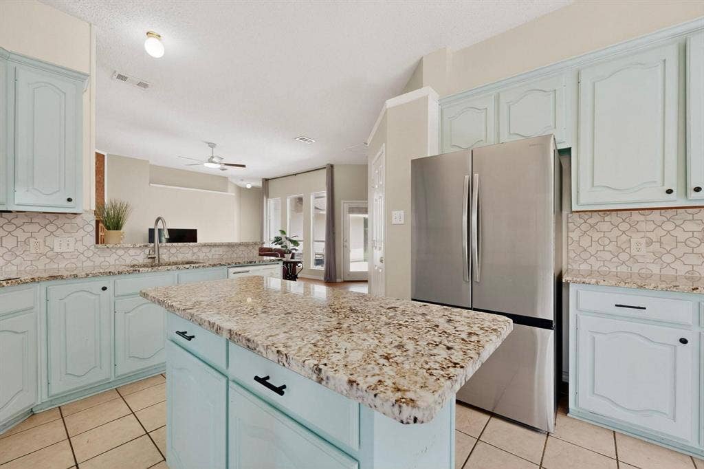 320 Elizabeth Trail, Murphy, TX 75094 Kitchen featuring light blue cabinetry, granite countertops, patterned tile backsplash, and a center island
