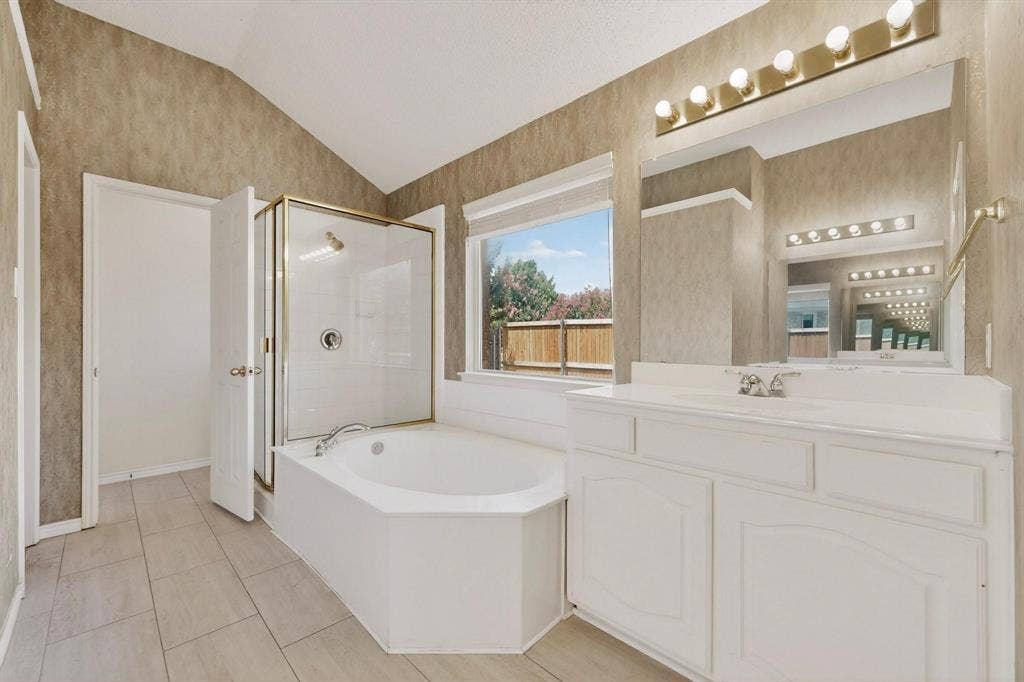320 Elizabeth Trail, Murphy, TX 75094 Vaulted ceiling bathroom featuring a built-in bathtub, glass-enclosed shower, dual vanity with integral sinks, and a large mirror with overhead lighting