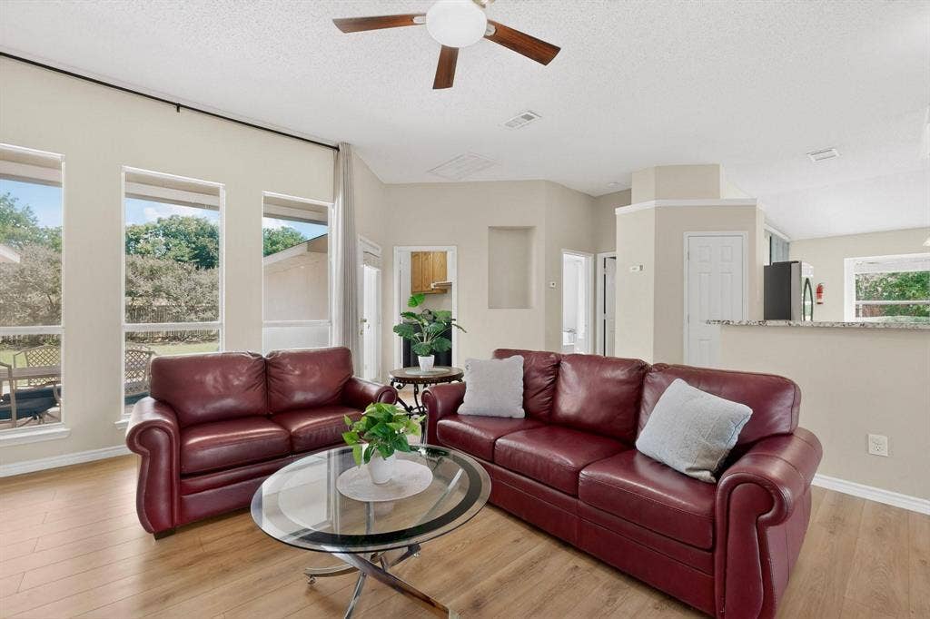 320 Elizabeth Trail, Murphy, TX 75094 Vaulted ceilings with a ceiling fan, light wood-finish flooring, multiple windows providing natural illumination, and a kitchen pass-through counter with a stone-finish surface
