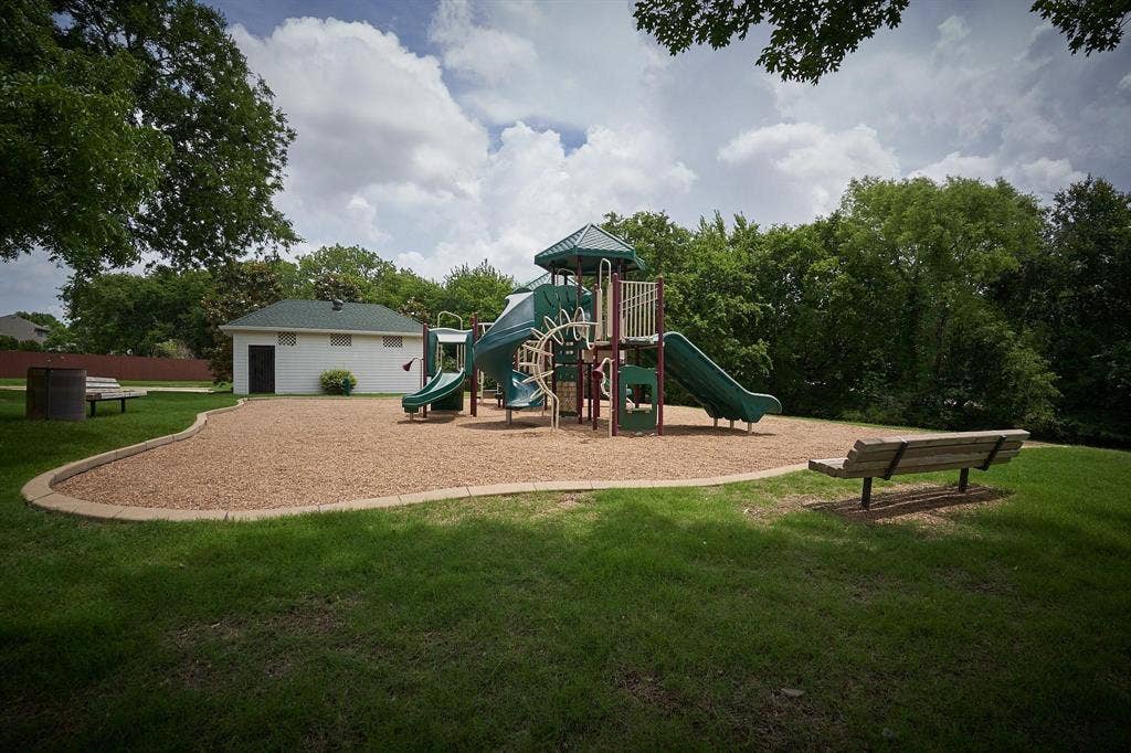 320 Elizabeth Trail, Murphy, TX 75094 Expansive recreational area featuring a playground with slides, a manicured lawn, and mature trees
