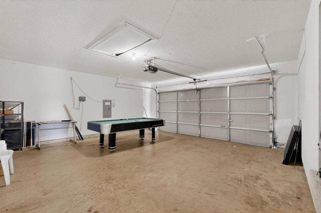 320 Elizabeth Trail, Murphy, TX 75094 Spacious garage with an overhead door, smooth concrete flooring, and an accessible attic opening