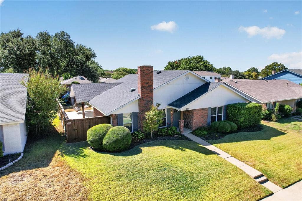 4448 Cleveland Drive, Plano, TX 75093 An elevated view showcases the home’s distinctive rooflines, prominent brick chimney and inviting outdoor spaces.