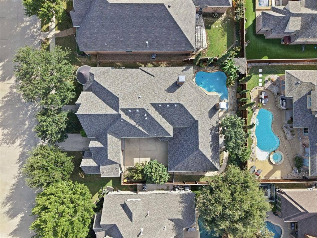 Aerial perspective featuring a multi-pitch shingled roof, a concrete driveway, a private swimming pool, and an attached garage