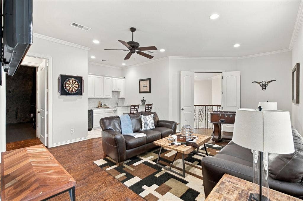 Living area featuring wood-finish flooring, recessed lighting, and a wet bar with white cabinetry and a stone-style backsplash