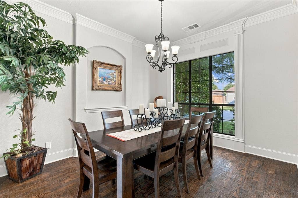 Dining room featuring dark wood-finish flooring, a wall niche with chair rail molding, crown molding, a multi-light chandelier, and expansive grid-pane windows