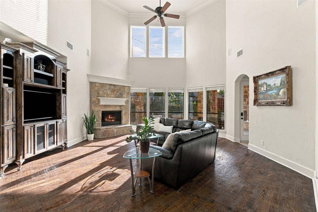 Vaulted ceilings featuring a built-in media center, stone fireplace, wood-finish flooring, and expansive windows