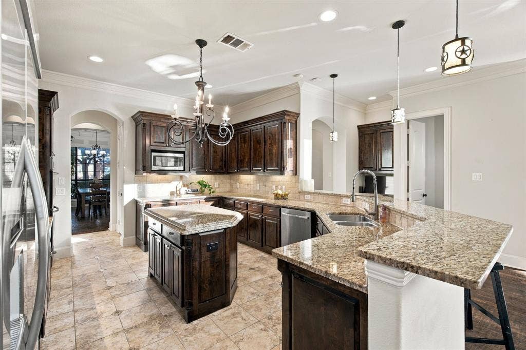 Kitchen featuring dark stained cabinetry, stone countertops, central island, tiled flooring, and arched doorways